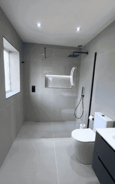 Walk-in shower with large gray tile and a built-in niche
