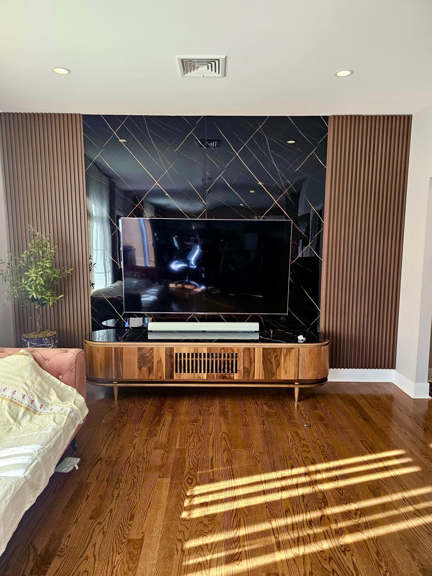 TV feature wall with geometric black panels and wood slat accents