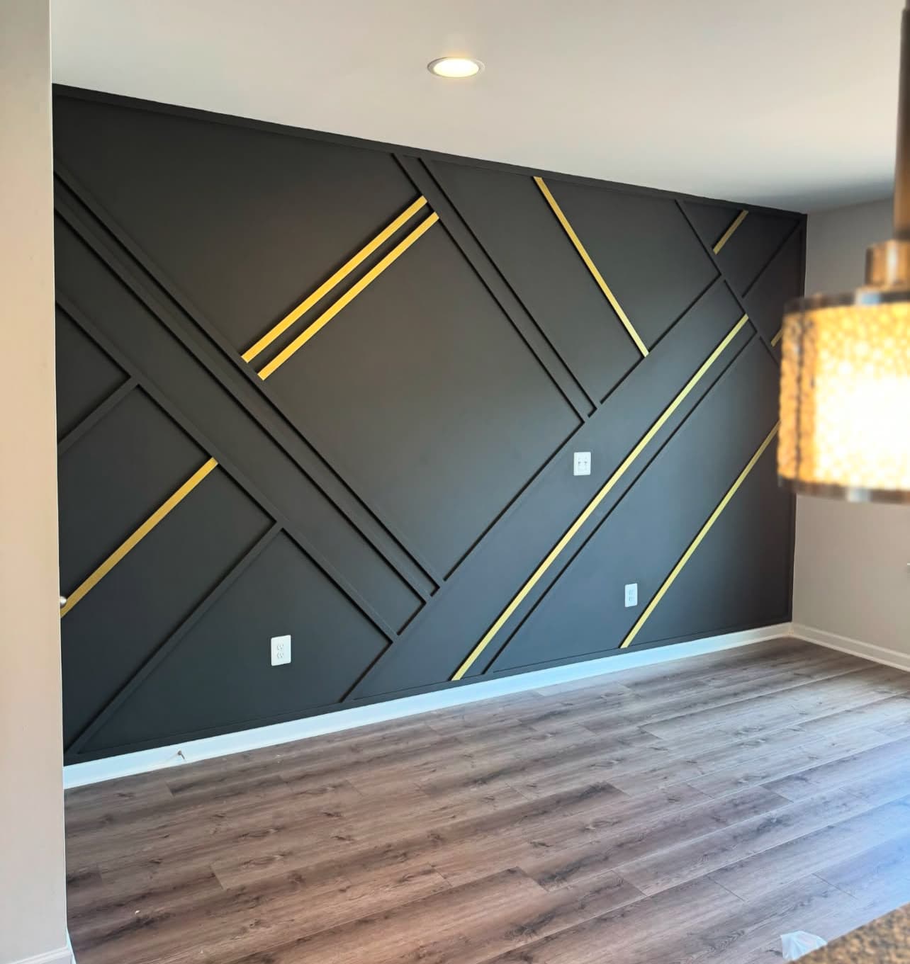 Black geometric accent wall with gold trim lines