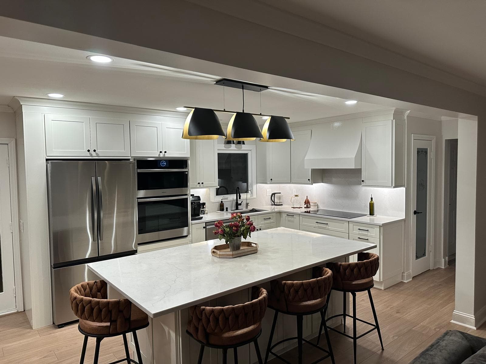 White kitchen with quartz island, black pendant lights and stainless appliances