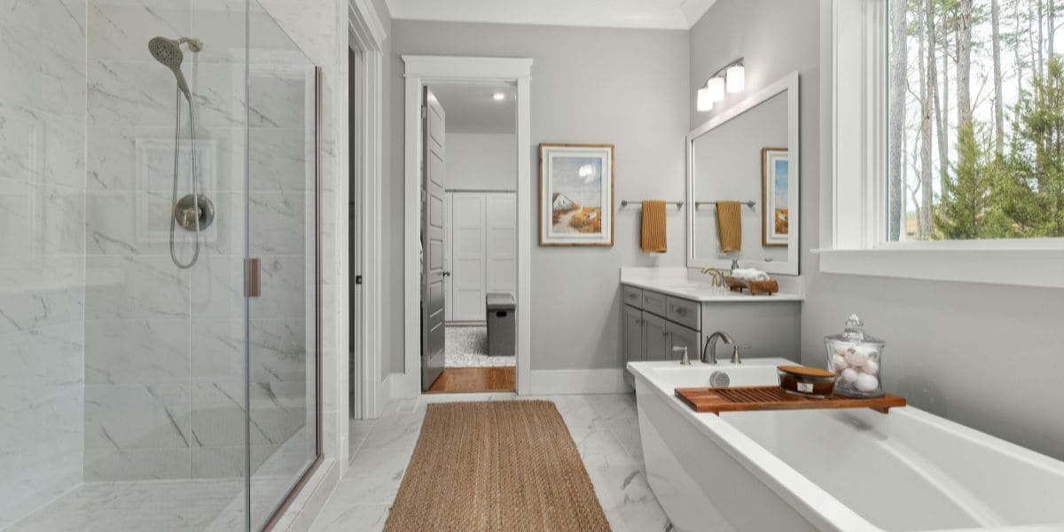 Bright bathroom with glass shower, soaking tub and marble-look tile